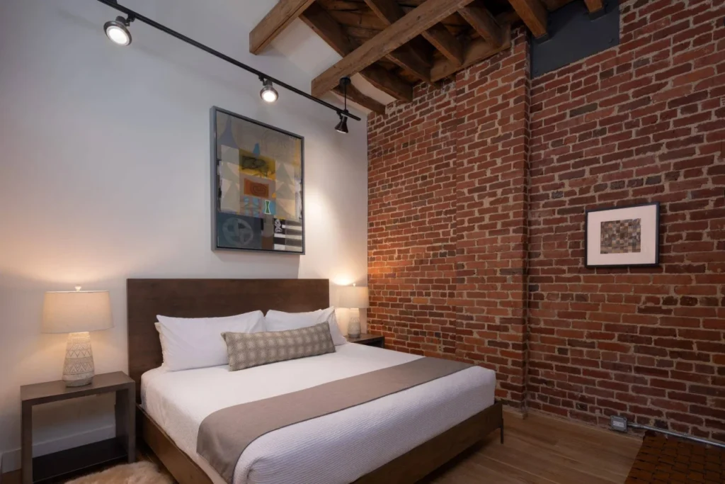Unit 303 king bedroom with exposed brick wall and original artwork, Elevation Lofts Hotel Asheville NC
